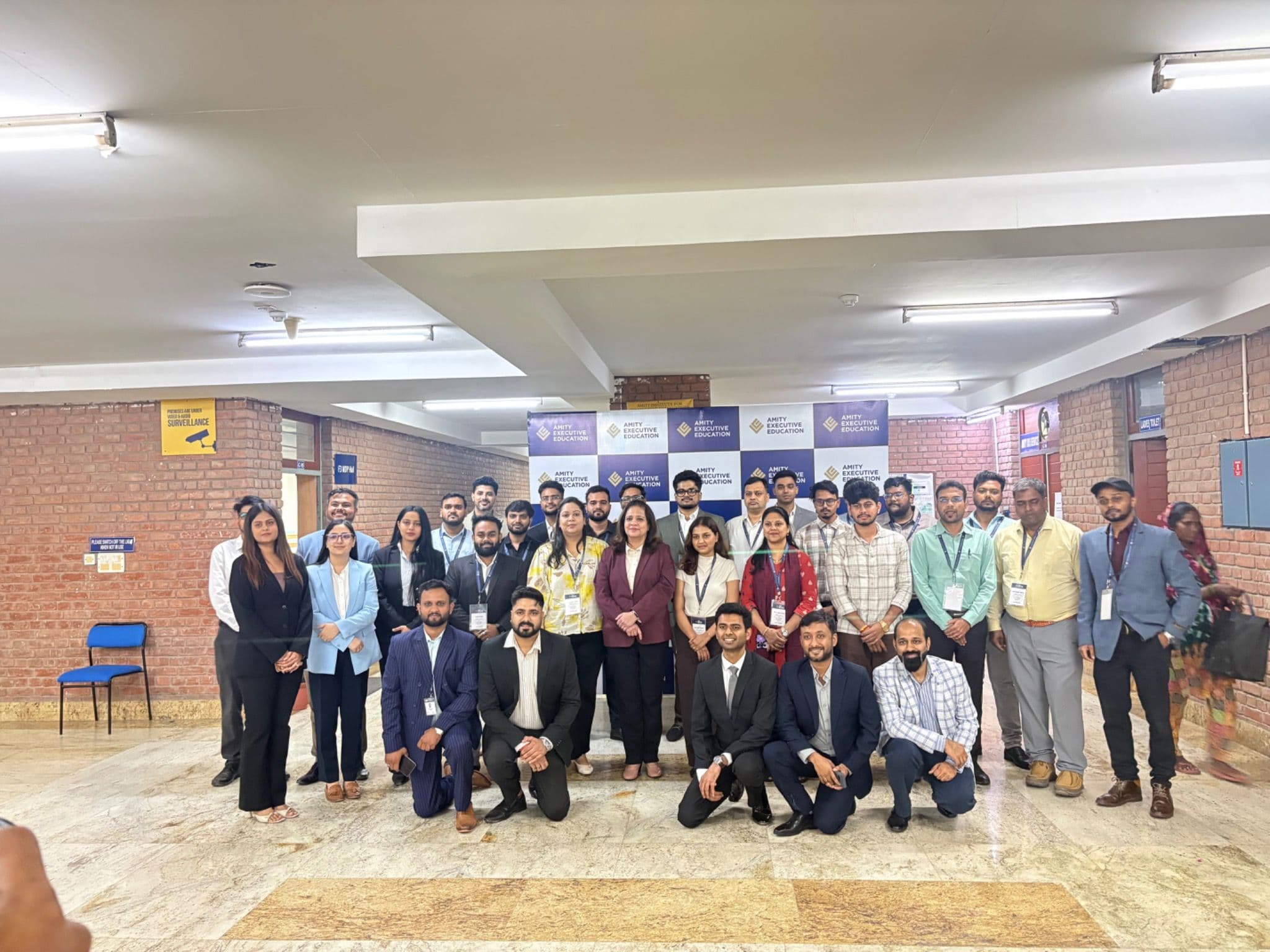 A group photograph in front of the Amity Executive Education backdrop.